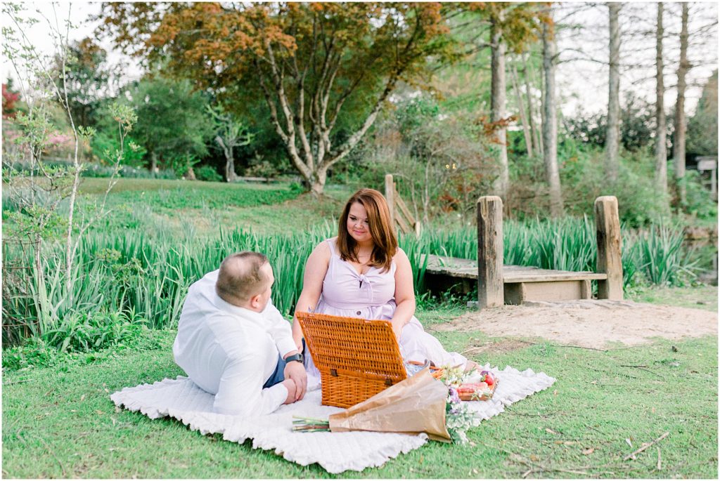 A couple having a picnic in the garden for engagement photos