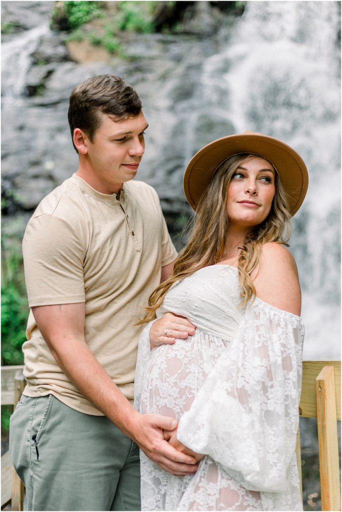 Couple in front of waterfall for maternity photos in amicalola falls